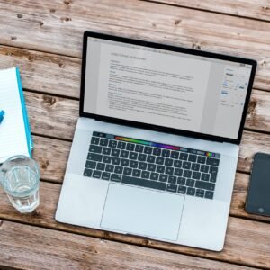 silver MacBook beside space gray iPhone 6 and clear drinking glass on brown wooden top